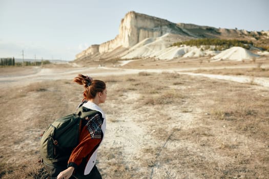 Adventurous woman hiking through a diverse landscape of fields, mountains, and desert