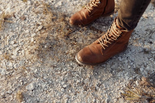 Lonely figure in brown boots stands on dusty desert road, embodying solitude and perseverance