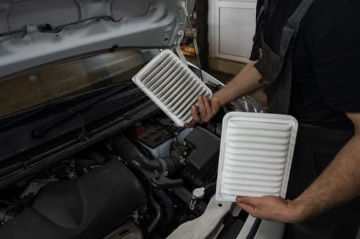 Mechanic holding old and new cabin air car filters