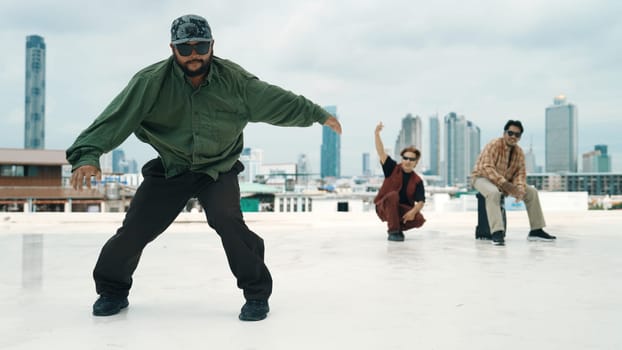 Professional break dance team practice B-boy dance while multicultural friends at rooftop. Young modern dancing group doing hip hop movement. Style,fashion,action. Outdoor sport 2024. Endeavor.