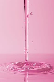 Pink liquid pouring into water with drop of pink liquid beauty and wellness concept