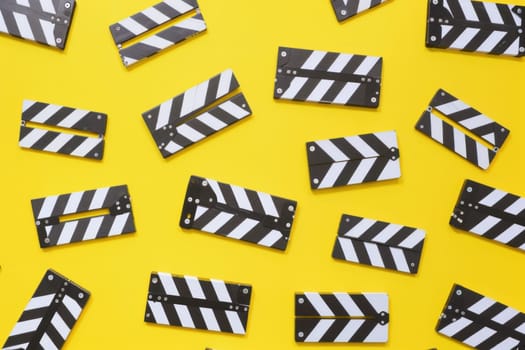 Black and white clapper boards on yellow background with stripes for filmmaking and media production