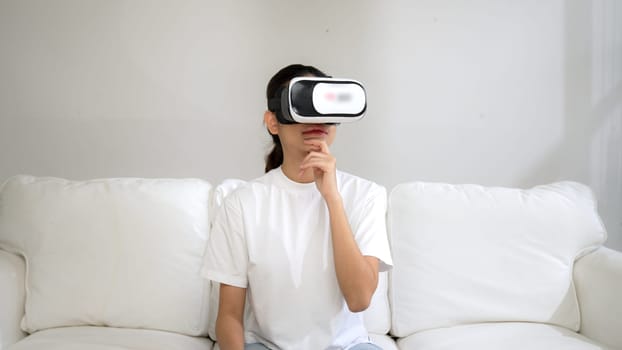 Young woman using virtual reality VR goggle at home for vivancy online shopping experience. The virtual reality VR innovation optimized for female digital entertainment lifestyle.