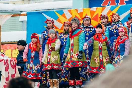 VICHUGA, RUSSIA - FEBRUARY 17, 2018: crowd of girls on stage sing songs in traditional Slavic costumes at the winter Russian celebration of the Maslenitsa holiday
