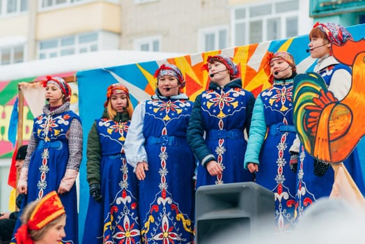 VICHUGA, RUSSIA - FEBRUARY 17, 2018: crowd of girls on stage sing songs in traditional Slavic costumes at the winter Russian celebration of the Maslenitsa holiday
