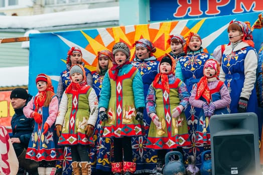 VICHUGA, RUSSIA - FEBRUARY 17, 2018: crowd of girls on stage sing songs in traditional Slavic costumes at the winter Russian celebration of the Maslenitsa holiday