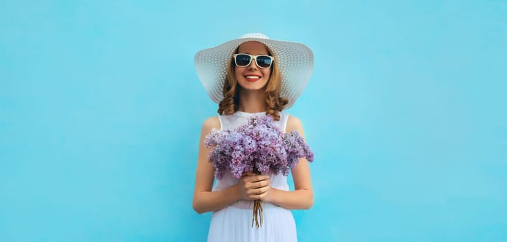 Summer portrait of beautiful lovely happy smiling woman with bouquet of purple lilac flowers in white straw hat on blue background