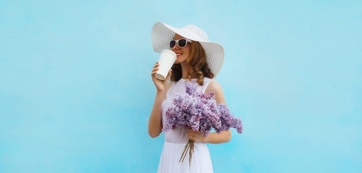 Summer portrait of beautiful lovely happy young woman with bouquet of purple lilac flowers drinking coffee in white straw hat on blue background