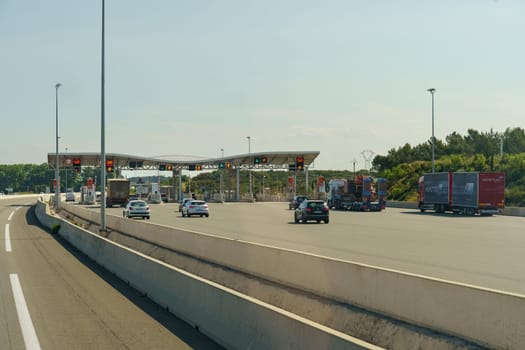 Salles-d'Aude, France - May 16, 2023: Cars and trucks drive through a toll booth on a sunny day.