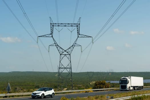 Nimes, France - May 16, 2023: A white truck is seen driving down a road that runs parallel to a power line, under a clear sky.