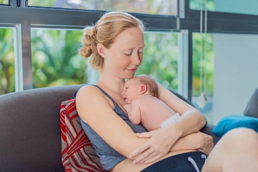 Mom with newborn baby relaxing on the sofa at home. This tender moment highlights the bond between mother and child in a comfortable and loving family environment.