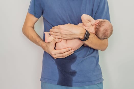 Dad holds newborn and newborn peed on dad. This humorous and heartwarming moment captures the realities of parenting and the bond between father and child in a candid family setting.