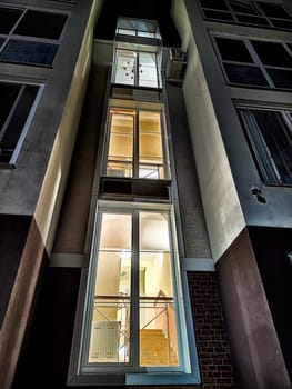 Warm light spills from the windows of city home at dusk. Illuminated Evening Façade of an Urban Residential Building