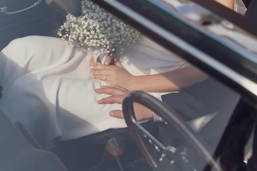 Bride with bouquet and ring in vintage car. Groom is driving cadillac