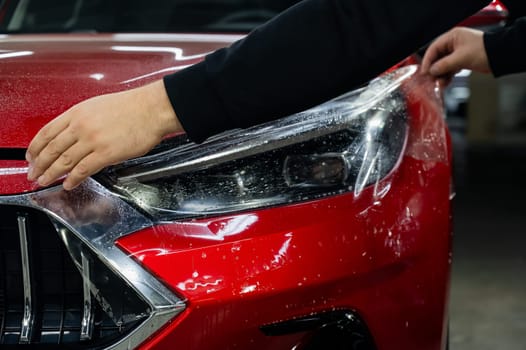 The process of applying protective vinyl film to car headlights in detailing