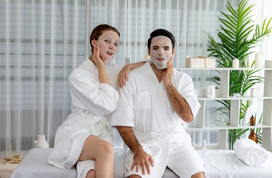 Serene modern daylight ambiance of spa salon, couple customer indulges in rejuvenating with facial skincare mask. Facial skin treatment and beauty cosmetology procedure for face. Quiescent