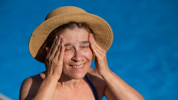 Portrait of an older woman applying sunscreen to her face while on vacation