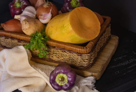 Freshly harvested vegetables in basket on black wooden table. Concept of healthy food. Still life image