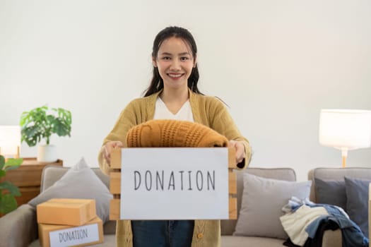 Smiling woman holding a donation box filled with clothes, symbolizing community support and generosity.