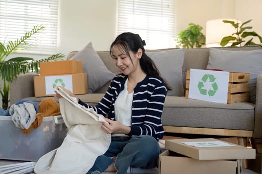 A young woman sorts through clothes to recycle and donate, emphasizing the importance of sustainability and community support.