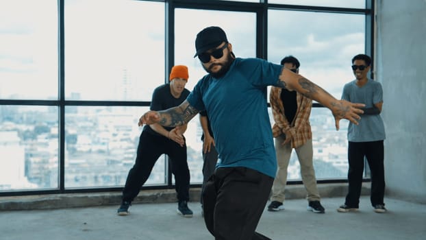 Multicultural hipster group looking at camera while perform break dancing at building with sky scrapper or city view. Street dancer team looking at dancer performance. Outdoor sport 2024. Endeavor.