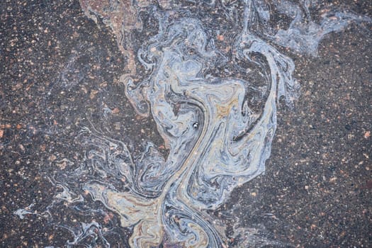 Colored oil stains close-up, color of a gasoline stain on asphalt as a texture or background.