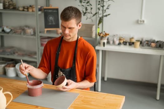 Potter paints ceramic dishes with a brush