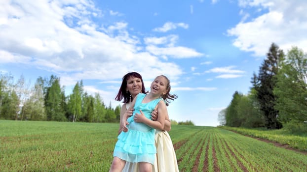 Happy mother and daughter enjoying rest, playing and fun on nature in green field. Woman and girl resting outdoors in summer or spring day