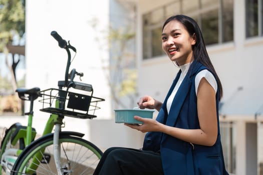 A young professional enjoying an eco-friendly lifestyle, featuring a bicycle and reusable lunch container in a modern urban environment.