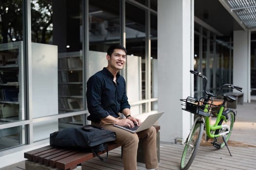 Young professional working on a laptop outdoors, promoting an eco-friendly business lifestyle with a bicycle and modern office setting.