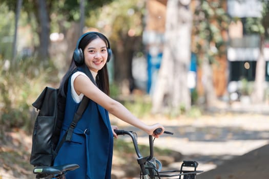 A young professional woman with headphones and a backpack rides a bicycle, promoting an eco-friendly lifestyle in an urban environment.