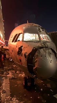 An aircraft from an aerospace manufacturer is parked at an airport at night, with automotive lighting illuminating the damaged airliner. Aviation event resulting in a grounded vehicle