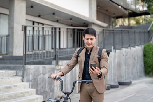 Businessman in a suit using a smartphone while standing with a bicycle, promoting eco-friendly and sustainable transportation in an urban environment.