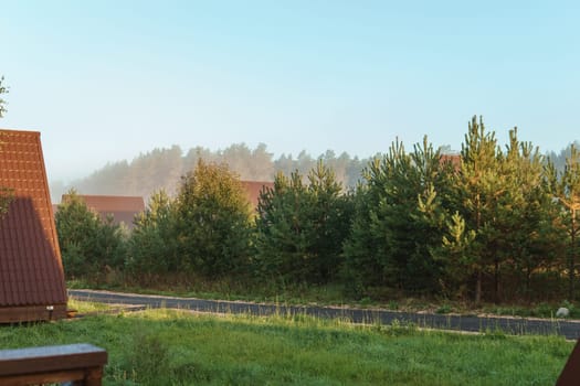 The concept of glamping and renting a chalet for weekend. Wooden house with a veranda in nature around coniferous trees.