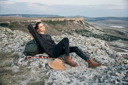 Adventure awaits woman enjoying the view on top of a mountain with backpack and hat