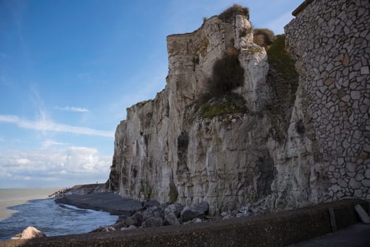 the chalk cliffs of etretat in France in Normandy with a blue sky with white clouds and the sea
