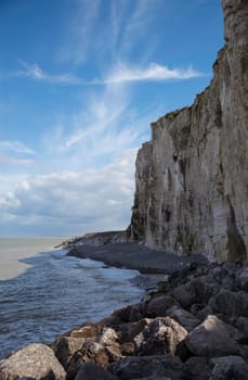 the chalk cliffs of etretat in France in Normandy with a blue sky with white clouds and the sea