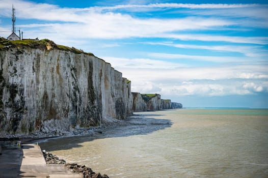 the chalk cliffs of etretat in France in Normandy with a blue sky with white clouds and the sea