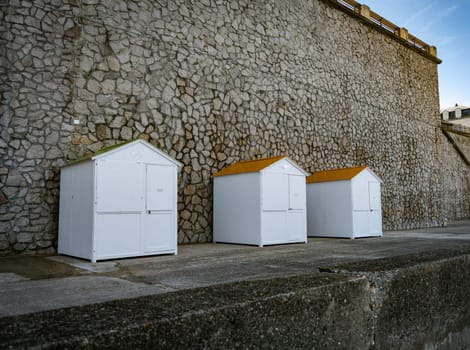 three white wooden beachhouses on the coastline of etretat in normandy in france with walls from rocks