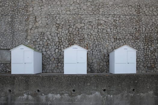 three white wooden beachhouses on the coastline of etretat in normandy in france with walls from rocks