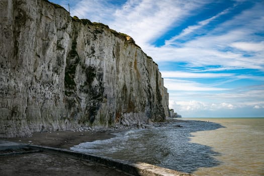 the chalk cliffs of etretat in France in Normandy with a blue sky with white clouds and the sea