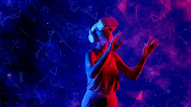 Excited smiling Asian woman looking around through VR metaverse with pointing on blue neon digital universe starry zodiac virtual space fantastic exploration nebula vibrant meta world. Hallucination.