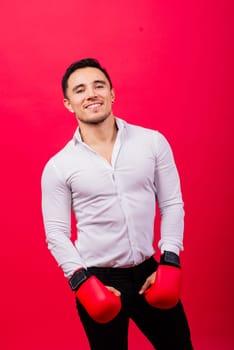 Handsome young businessman with a boxing gloves. Studio red background