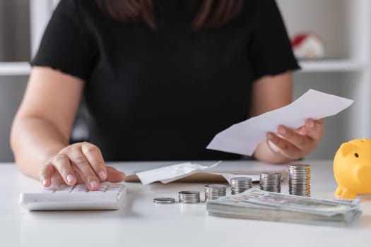 Young woman planning to save money with calculator, coins, and piggy bank on desk, focusing on financial planning and budgeting.