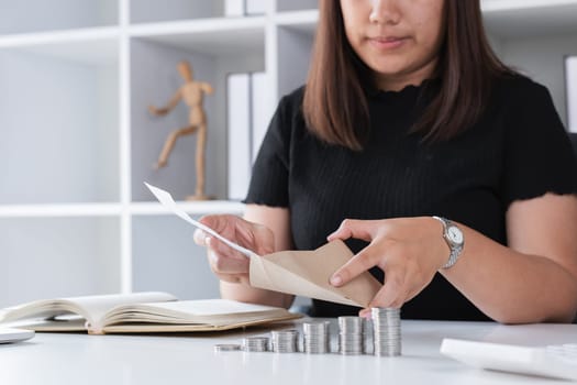 Young woman counting coins and organizing finances at home office desk, representing financial planning and budgeting.