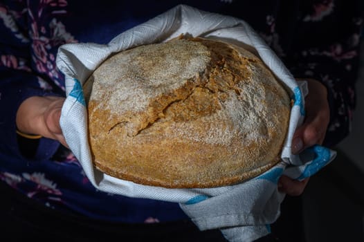 Woman holding freshly baked bread on black background, closeup 2