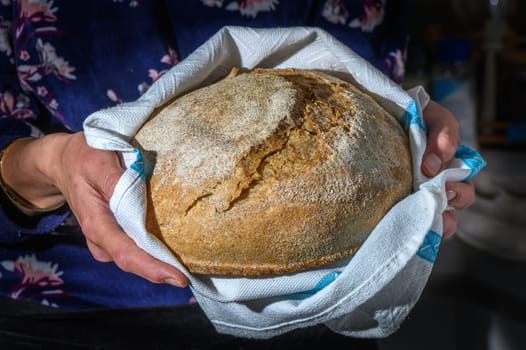 Woman holding freshly baked bread on black background, closeup 1