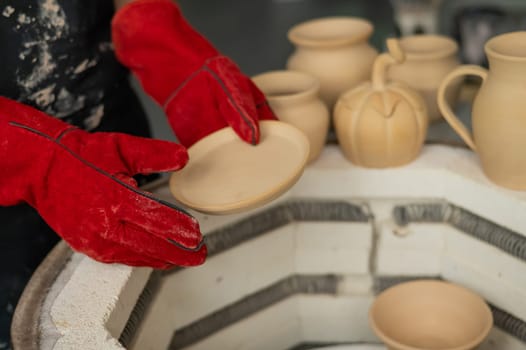 Close-up of a man's hands loading ceramics into a special kiln