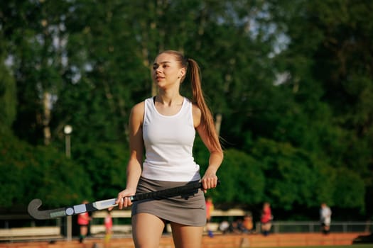 girl hockey player plays field hockey on a sunny day, female hockey player hits the ball with a stick, field hockey concept