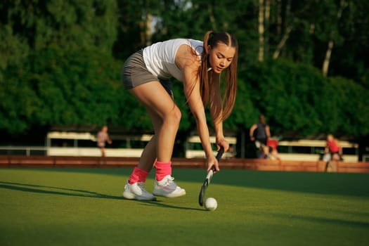 girl hockey player plays field hockey on a sunny day, female hockey player hits the ball with a stick, field hockey concept